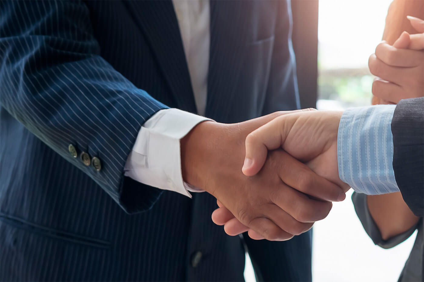Close-up of two people in suits shaking hands, symbolizing agreements or partnerships, potentially related to discussions on escrow services, corporate actions, and corporate escrow support.