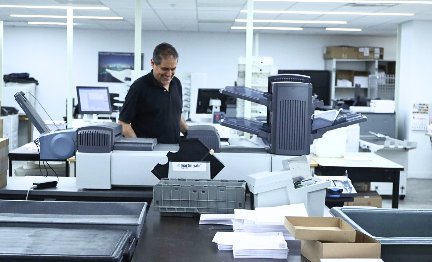 Mailroom operations employee printing envelopes and proxy cards for annual meetings.